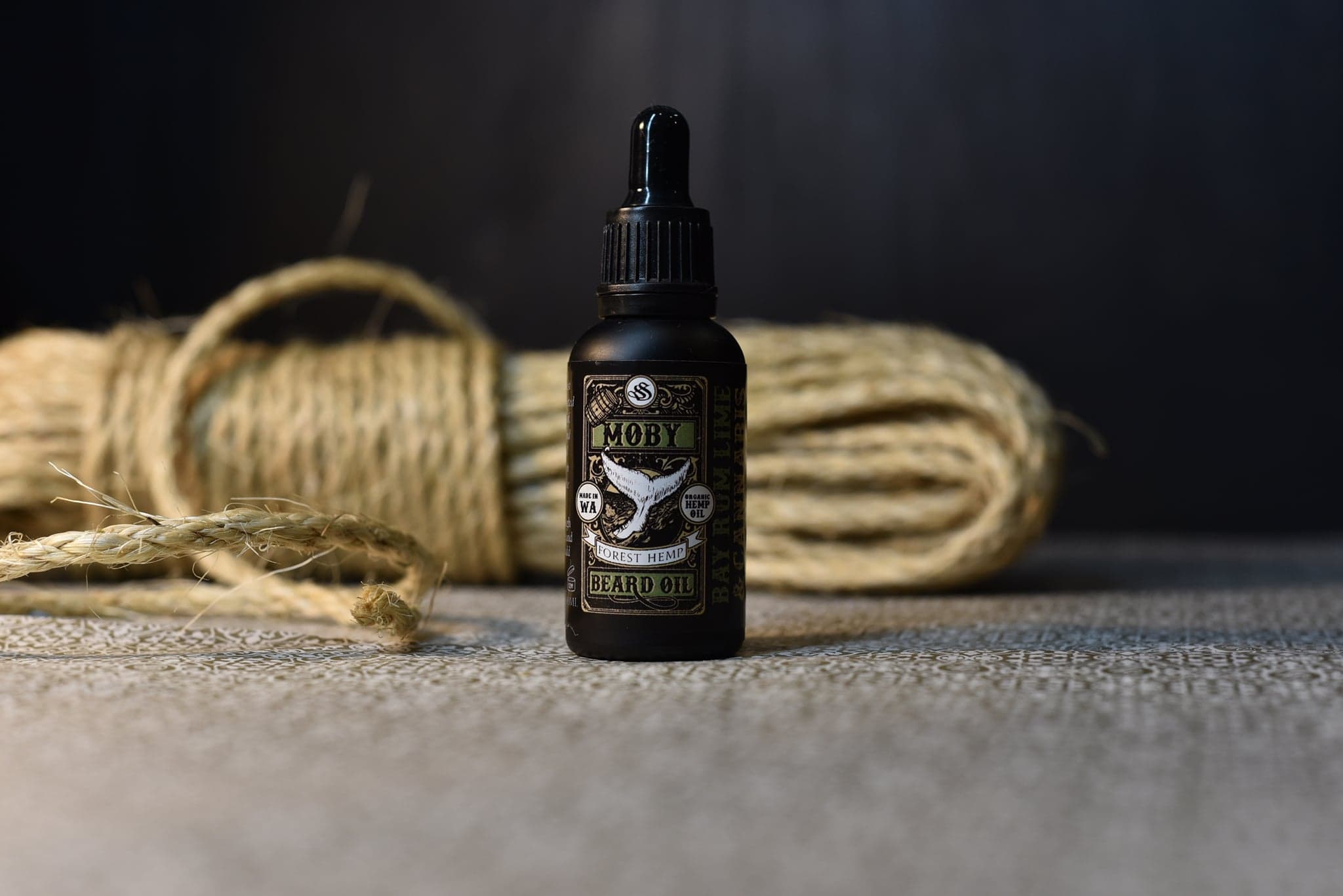 Moby beard oil in a black dropper bottle, resting against a coil of rope