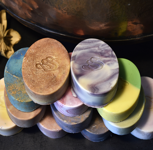 A stack of coloured oval soap bars, each stamped with the Forest Hemp Soapsmith monogram