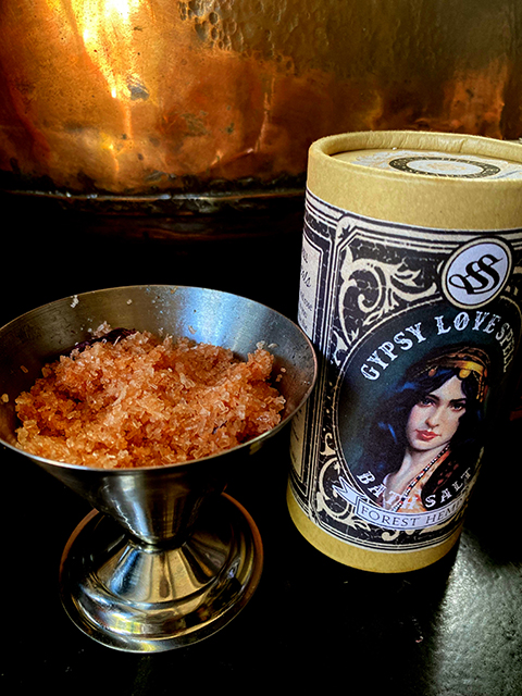 Gypsy Love Spell bath salts in a printed tube, beside a small dish of salts